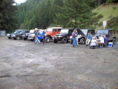 1976 Ford F-100 - A group of people are gathered around several off-road vehicles in a parking area.