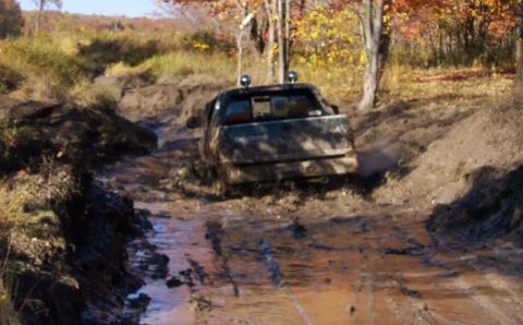 1979 Ford Bronco - Off-road vehicle navigates a difficult muddy path during autumn.