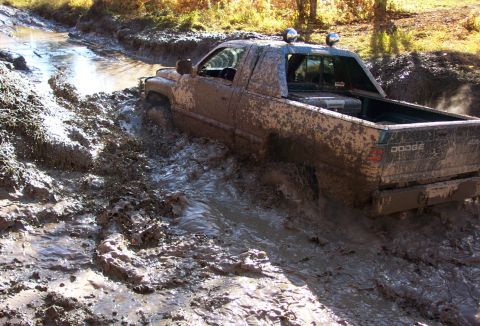 1979 Ford Bronco - This Dodge pickup is deep in the mud, with water and muck splashing around its tires.