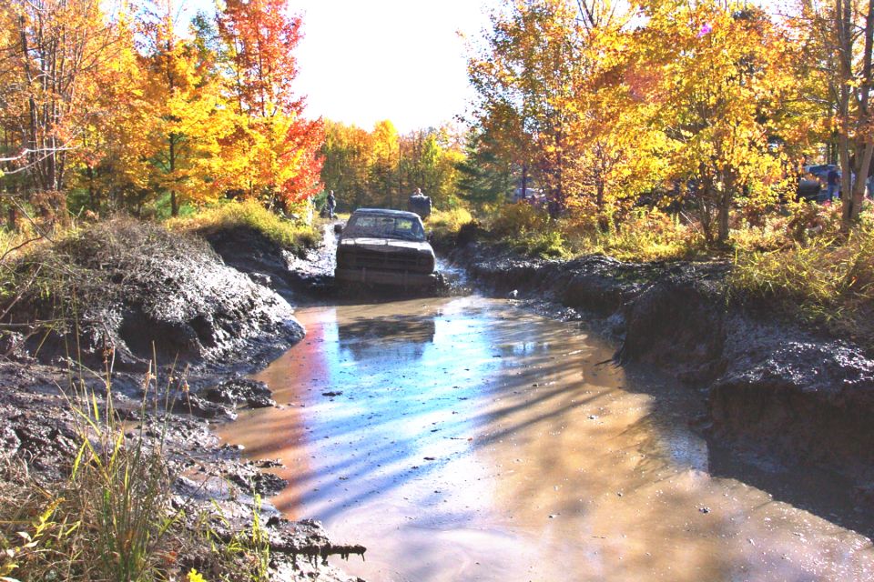 Truck driving through mud puddle with fall foliage