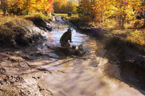 1979 Ford Bronco - An ATV navigates a deep mud pit during an off-road excursion.