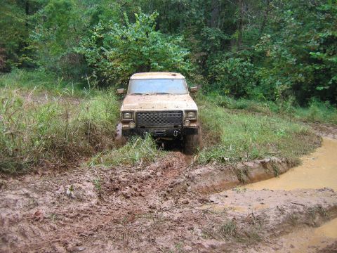 1992 Ford Mustang - This vehicle is navigating a muddy trail with dense foliage surrounding it.