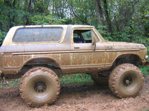 1992 Ford Mustang - This lifted SUV is covered in mud after driving through a wet, wooded area.