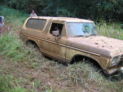 1992 Ford Mustang - A muddy 1978 Ford Bronco is stuck in the mud with a person standing in the background.