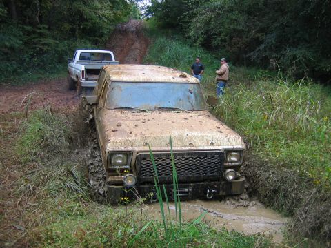 1992 Ford Mustang - A mud-covered 1979 Ford F-Series truck is stuck in a muddy ditch while another truck waits behind it.