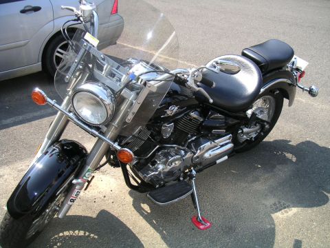 1994 Ford Bronco - A black motorcycle is parked on asphalt, with a silver car visible in the background.