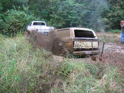 1992 Ford Mustang - Two trucks are stuck in the mud, with one vehicle spraying a large amount of water.