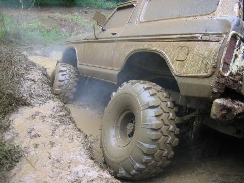 1992 Ford Mustang - A heavily muddied 1978 Ford Bronco struggles for traction in a muddy off-road track.