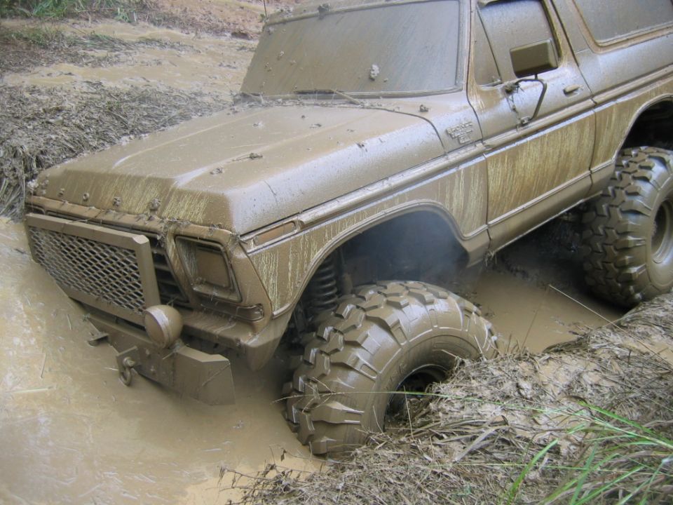 Mud-covered 1978 Ford Bronco stuck deep in mud, front grille and tires visible