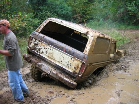 1992 Ford Mustang - A man watches as a mud-covered 1978 Ford Bronco struggles in deep mud.