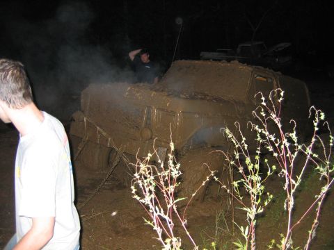 1992 Ford Mustang - A heavily mud-covered vehicle appears stuck in the mud at night, with two people nearby.