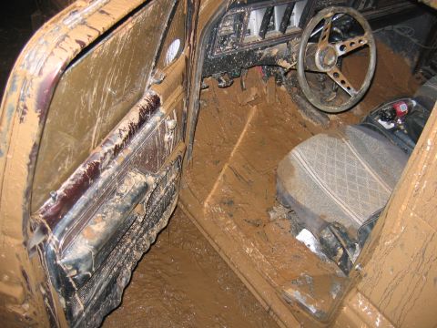 1992 Ford Mustang - The interior of a vehicle is completely covered in mud, obscuring most details.