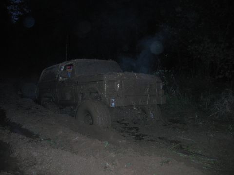 1992 Ford Mustang - An SUV is stuck in the mud at night, with its tires submerged and mud splattered all over its body.