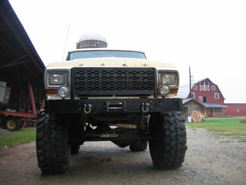 1992 Ford Mustang - A heavily modified pickup truck sits in front of farm buildings under an overcast sky.