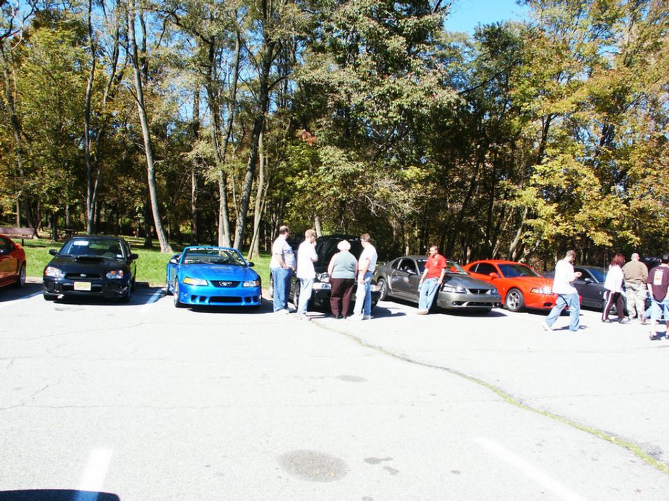 Blue Ford Mustang GT convertible parked in lot with other cars and people