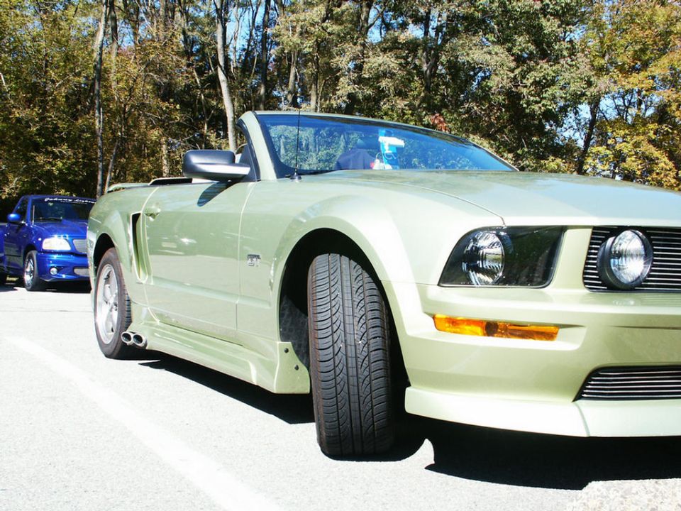 Light green convertible with a blue pickup truck behind it