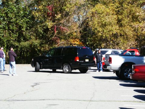 2001 Mercury Grand Marquis - Several vehicles are parked in a lot with trees in the background.