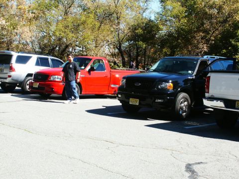 2001 Mercury Grand Marquis - A red 2001 Ford F-150 SVT Lightning pickup truck is parked at an outdoor event with other vehicles.