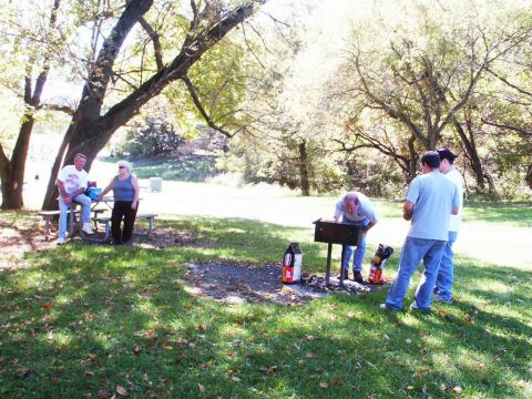 2001 Mercury Grand Marquis - A group of people enjoy a picnic and barbecue in a park setting on a sunny day.