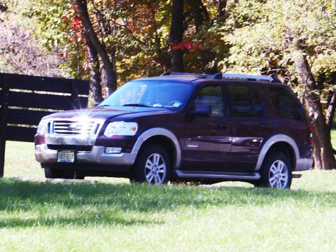 2001 Mercury Grand Marquis - Maroon Ford Explorer SUV parked on a grassy area with trees in the background.