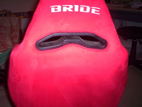 1998 Ford Crown Victoria - Front view of a red suede Bride bucket racing seat showing the white BRIDE logo and the shoulder harness pass-through slot.