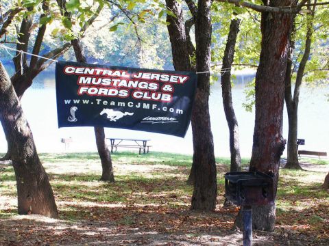 2001 Mercury Grand Marquis - Banner for Central Jersey Mustangs & Fords Club hangs between trees at an outdoor event.