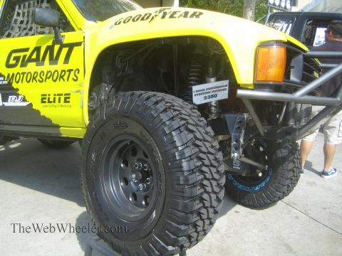 1990 Ford Bronco - Close view of a yellow GIANT Motorsports Toyota prerunner showing a Goodyear-lettered fender, black beadlock wheel and oversized mud tire.