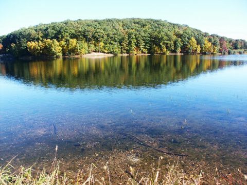 2001 Mercury Grand Marquis - A calm lake reflects a tree-covered hill under a clear blue sky.