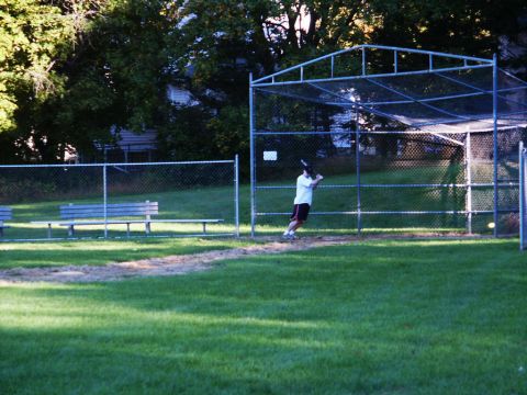 2001 Mercury Grand Marquis - A person practices batting in a cage at a park on a sunny day.