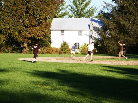 2001 Mercury Grand Marquis - A group of people engage in a game of baseball on a sunny day, with a house visible in the background.
