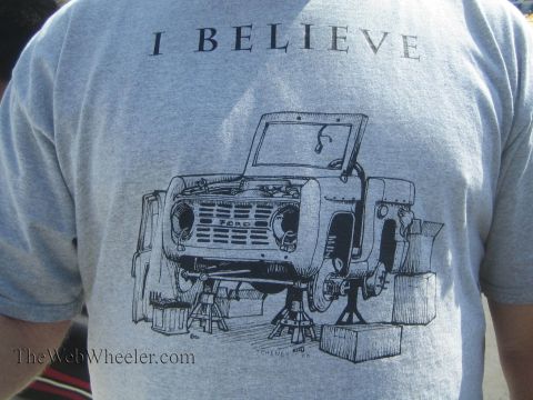 1990 Ford Bronco - back of a gray T-shirt reads I BELIEVE above a black line drawing of an early Ford Bronco on jack stands being worked on.