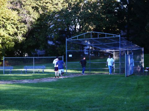 2001 Mercury Grand Marquis - People are playing baseball on a field with a backstop and trees in the background.