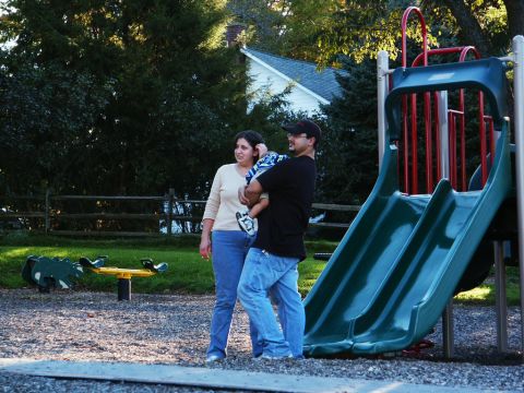 2001 Mercury Grand Marquis - A family enjoys a day at the playground, with a slide and seesaw visible.