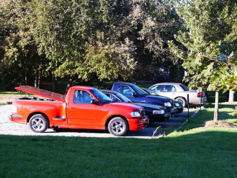 2001 Mercury Grand Marquis - Three cars are parked in a grassy area next to trees.
