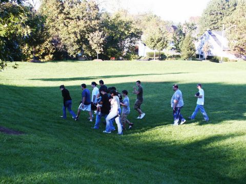 2001 Mercury Grand Marquis - A group of people stroll across a sun-dappled lawn on a clear day, with houses visible in the distance.