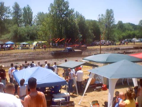 1976 Ford F-100 - A 1976 Ford F-100 navigates a muddy track during a race event, with spectators gathered around.