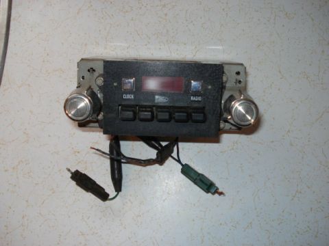 1979 Ford Bronco - This car radio features two prominent knobs, a row of five buttons, and a digital display. Text labels indicate CLOCK and RADIO functions.