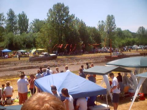 1976 Ford F-100 - Muddy event with a 1976 Ford F-100 truck, tents, and spectators under a clear sky.