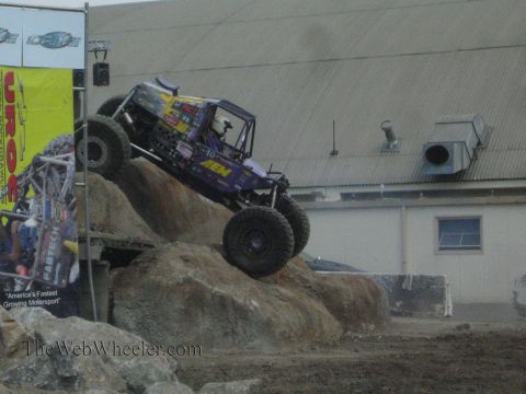 1990 Ford Bronco - purple tube-frame rock buggy with AEM markings crests a boulder during a UROC rock-crawling run.