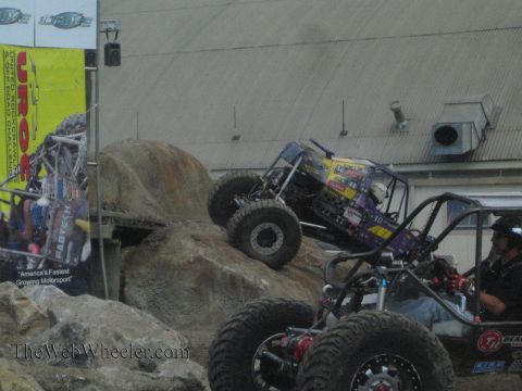 1990 Ford Bronco - purple rock buggy crawls a boulder while a driver pilots a second tube-chassis buggy in the foreground at a UROC event.