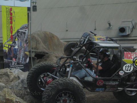 1990 Ford Bronco - helmeted driver sits in a black tube-chassis rock buggy marked 123 with Mickey Thompson and beadlock branding.