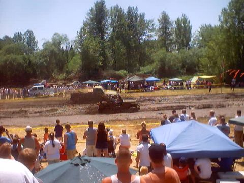1976 Ford F-100 - Spectators watch vehicles compete in a mud bog event on a sunny day.