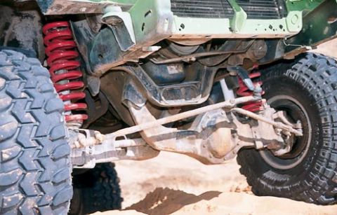 1984 Ford Bronco - The undercarriage of an off-road vehicle shows heavy-duty suspension components and large tires.