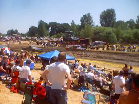 1976 Ford F-100 - Spectators watch trucks compete in a mud bog event, with a 1976 Ford F-100 visible among the vehicles.