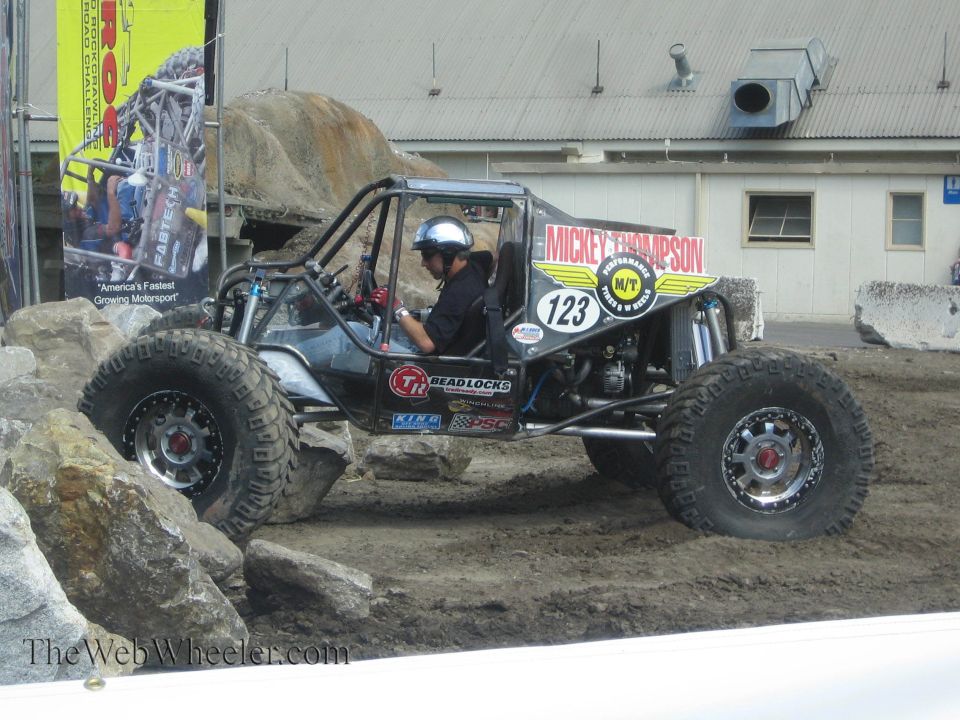 Black tube-chassis rock buggy number 123 with Mickey Thompson decals climbing rocks