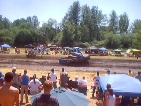 1976 Ford F-100 - Spectators watch trucks compete in a mud bog event on a sunny day.