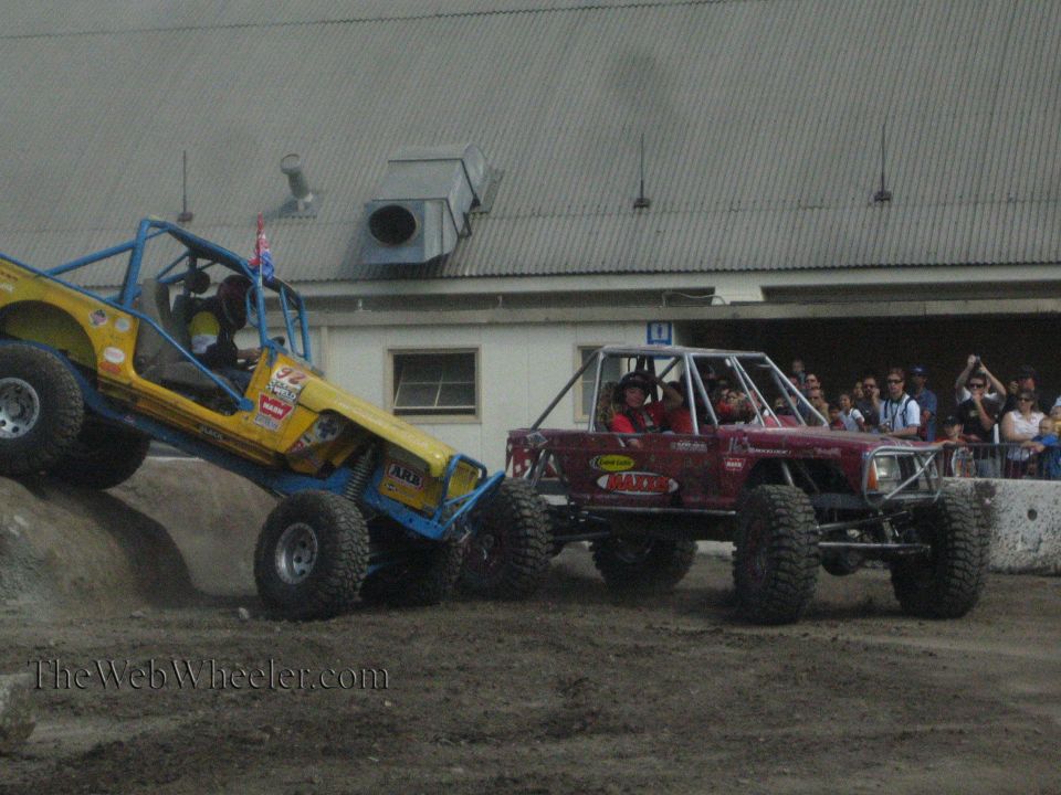 Yellow buggy and maroon buggy side by side on a dirt course with spectators