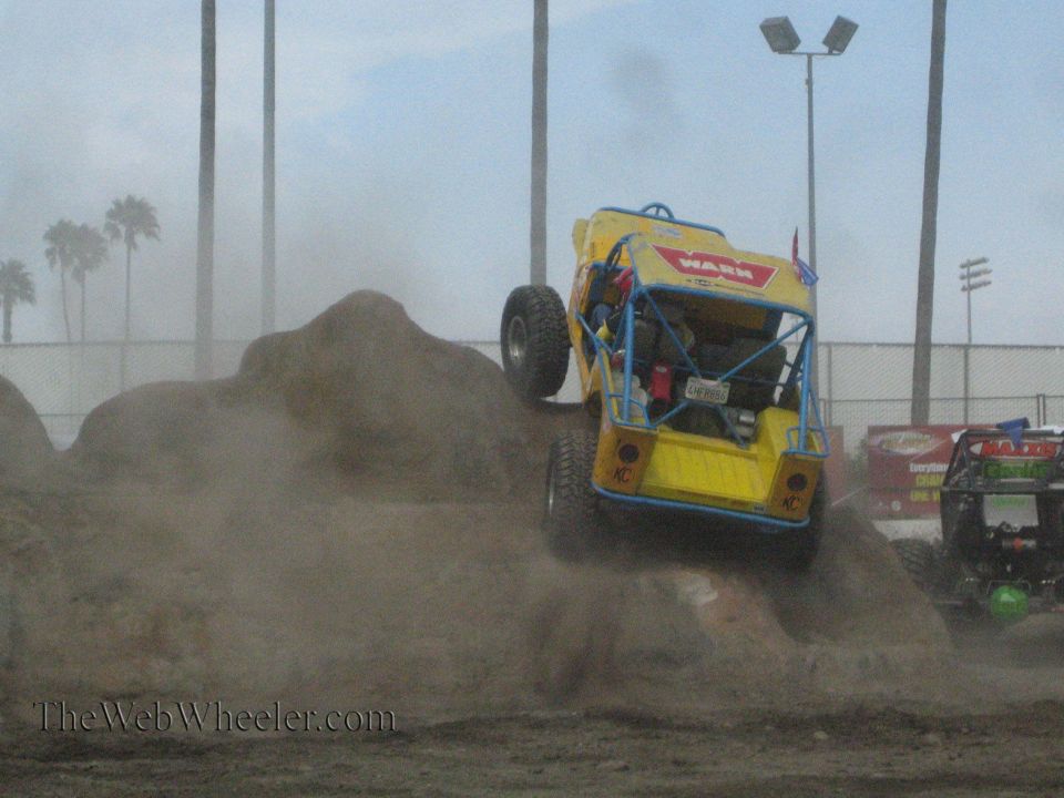 Yellow Warn buggy front view climbing a dirt mound with another buggy at right