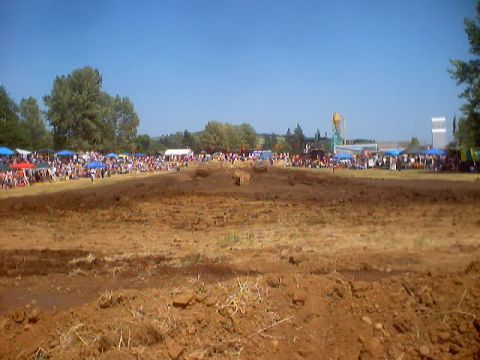 1976 Ford F-100 - A wide view of a muddy motocross track during an event, with spectators gathered along the sidelines.