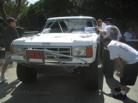1990 Ford Bronco - Spectators inspect a white off-road prerunner pickup with a For Sale sign and tube front bumper at an outdoor show.